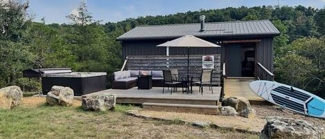 A wooden deck with outdoor furniture, a hot tub, and a surfboard.