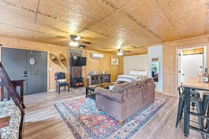 Interior rústico de una cabaña con techo de madera, un sofá, una mesa de comedor y un televisor.
