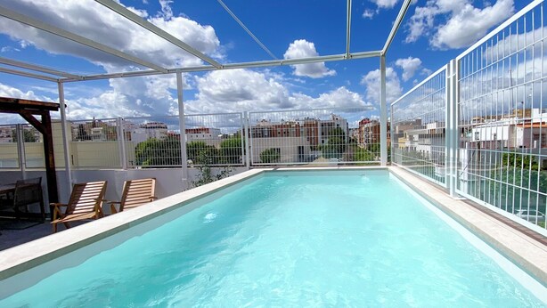 A rooftop swimming pool with a clear view of the cityscape in the background.