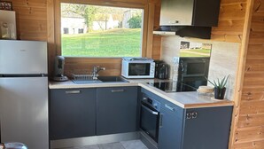 Cocina compacta equipada con refrigerador, microondas, lavaplatos y horno.