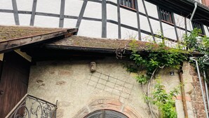 A traditional half-timbered building with a large wooden door and a small balcony.