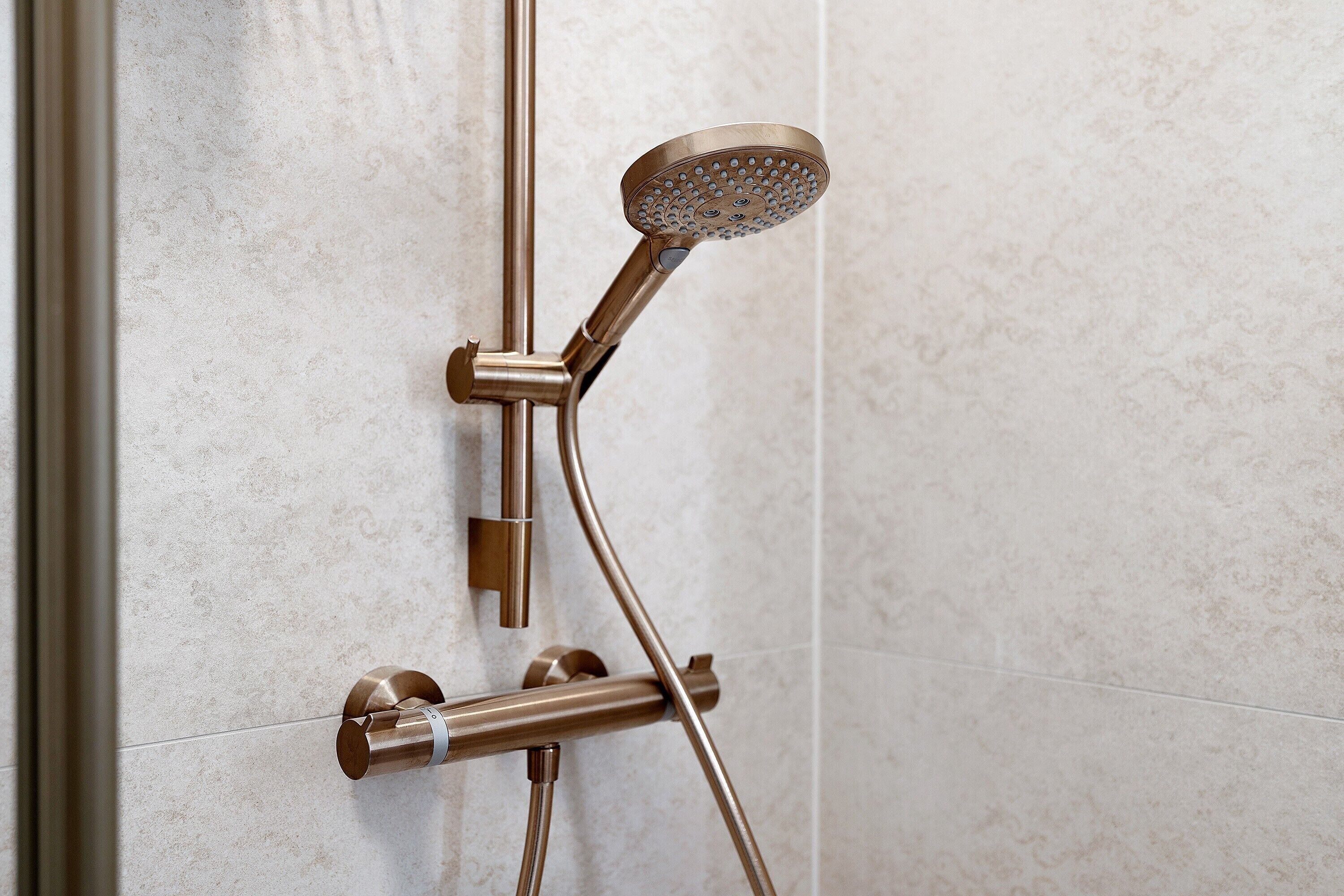A showerhead with a curved design, mounted on a wall with a textured surface.