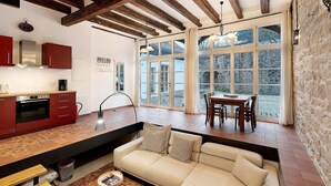 A modern kitchen with red cabinets, a built-in oven, and a dining area with a table and chairs.