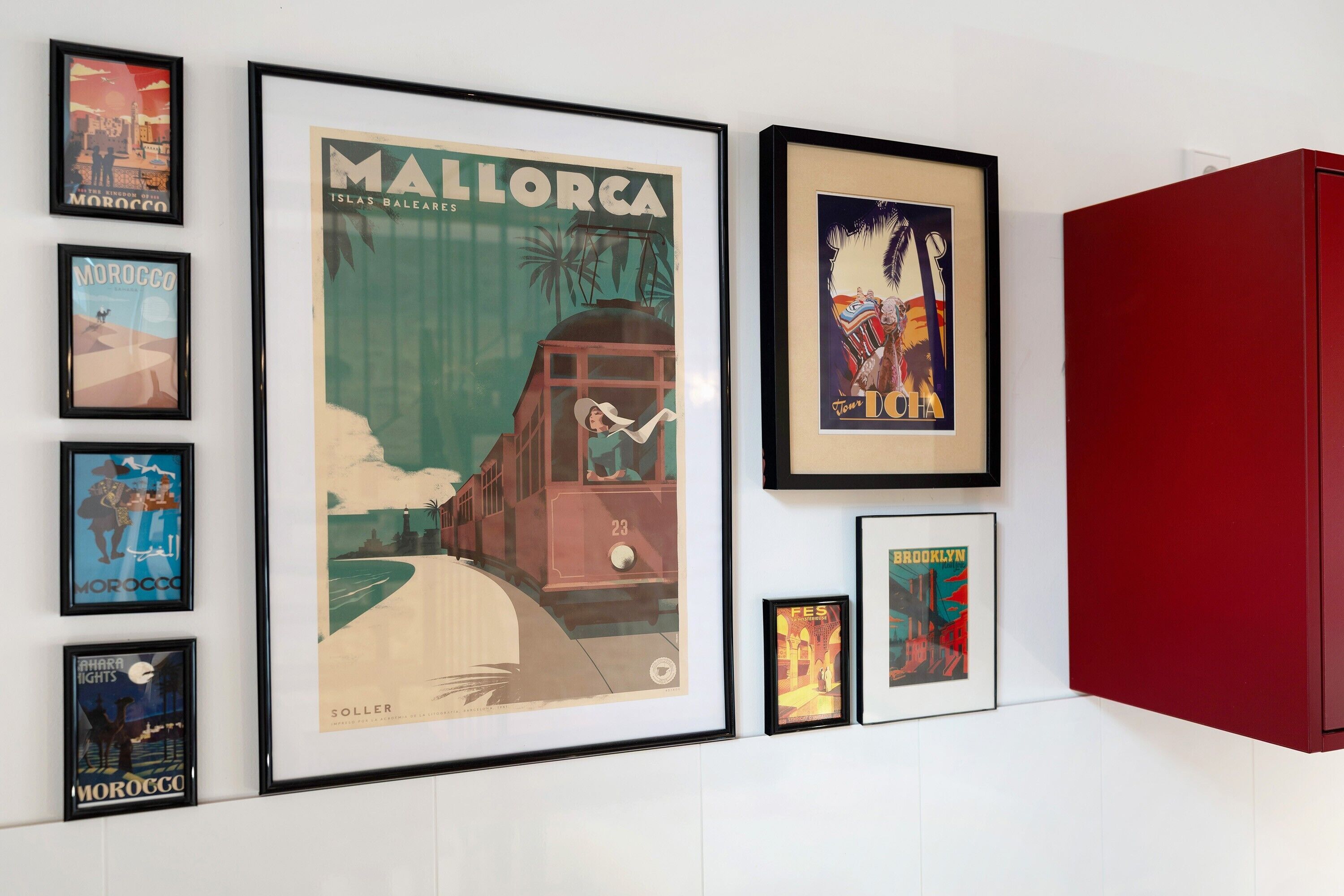 A wall with framed travel posters, including one for Mallorca and another for Brooklyn.