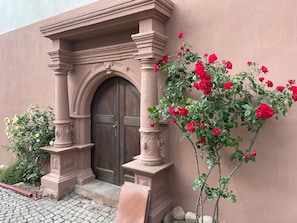 Un bâtiment doté d’une porte en bois, de colonnes en pierre et d’un rosier.