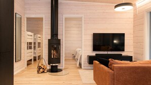 A modern living room with a wood-burning stove, a TV, and a sofa. - Modern 3BR Villa Retreat in Ruka with Private Sauna & Near Ski Slopes (Ruka)