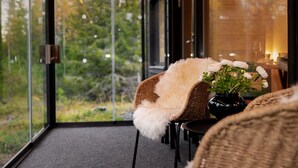A cozy room with a large window, a wicker chair, a small table, and a vase with flowers. - Modern 3BR Villa Retreat in Ruka with Private Sauna & Near Ski Slopes (Ruka)