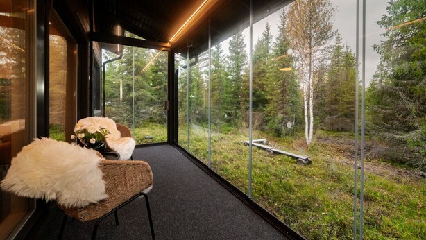 A modern interior with a large glass window offering a view of a forested area. - Modern 3BR Villa Retreat in Ruka with Private Sauna & Near Ski Slopes (Ruka)