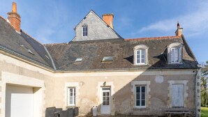 A two-story building with a sloped roof, a front door, and a small porch with a bench. - Le gite de Fontiville near the Loire castles (6 to 8 people) (Veigné)