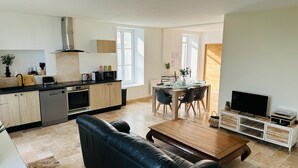 A modern kitchen with a dining area, a leather sofa, and a TV in a wooden cabinet. - Le gite de Fontiville near the Loire castles (6 to 8 people) (Veigné)