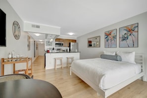 A modern bedroom with a large bed, a small kitchenette, and a dining area. - 2 Beds Waterfront Condo & Balcony | Heated Pool! (Tampa)