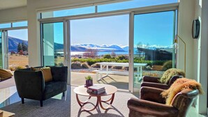 A modern living room with a large sliding glass door leading to a balcony with a mountain view.