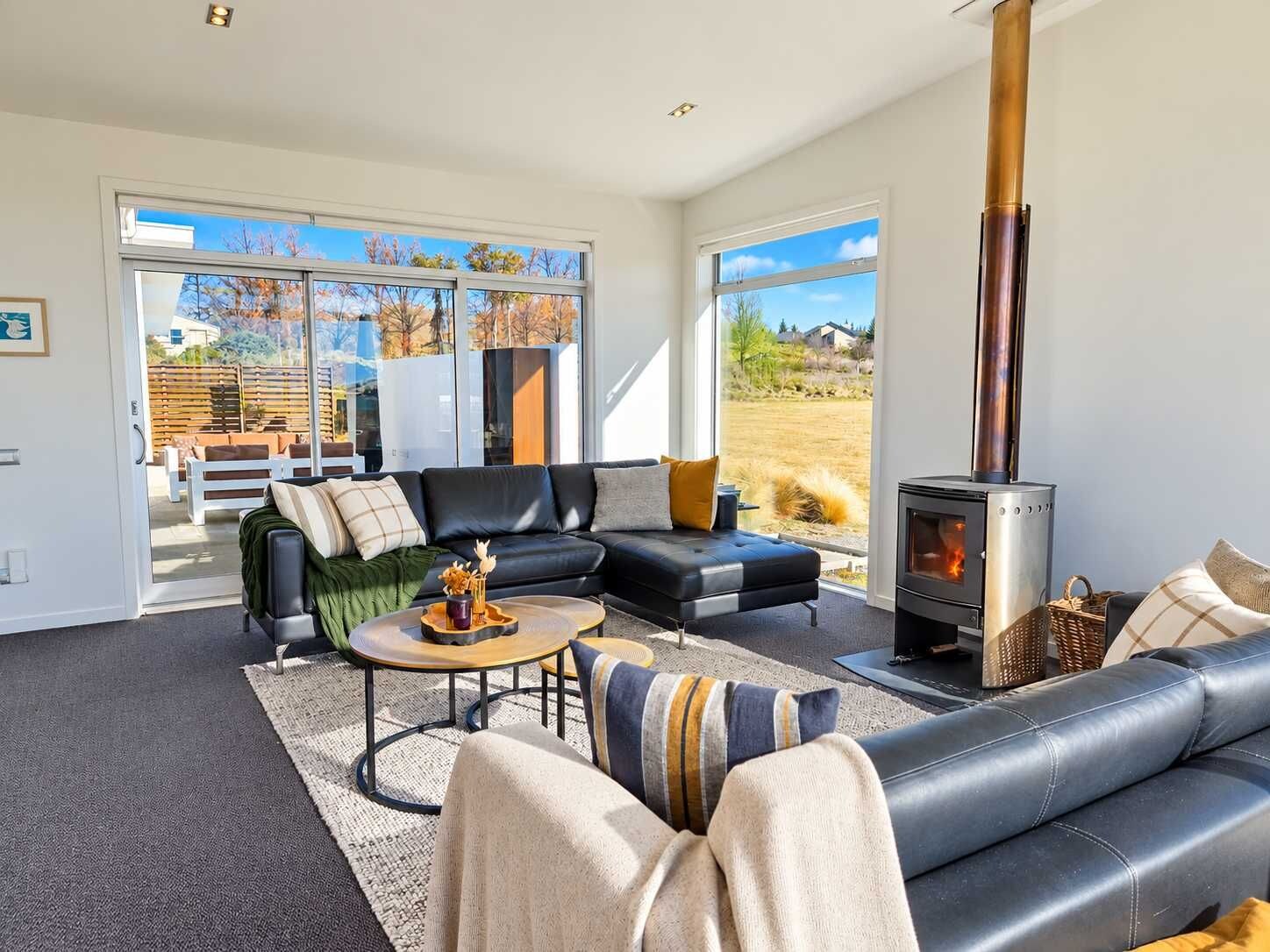 A modern living room with a fireplace, leather sofas, and a view of the outdoors.