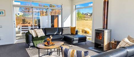 A modern living room with a fireplace, leather sofas, and a view of the outdoors.