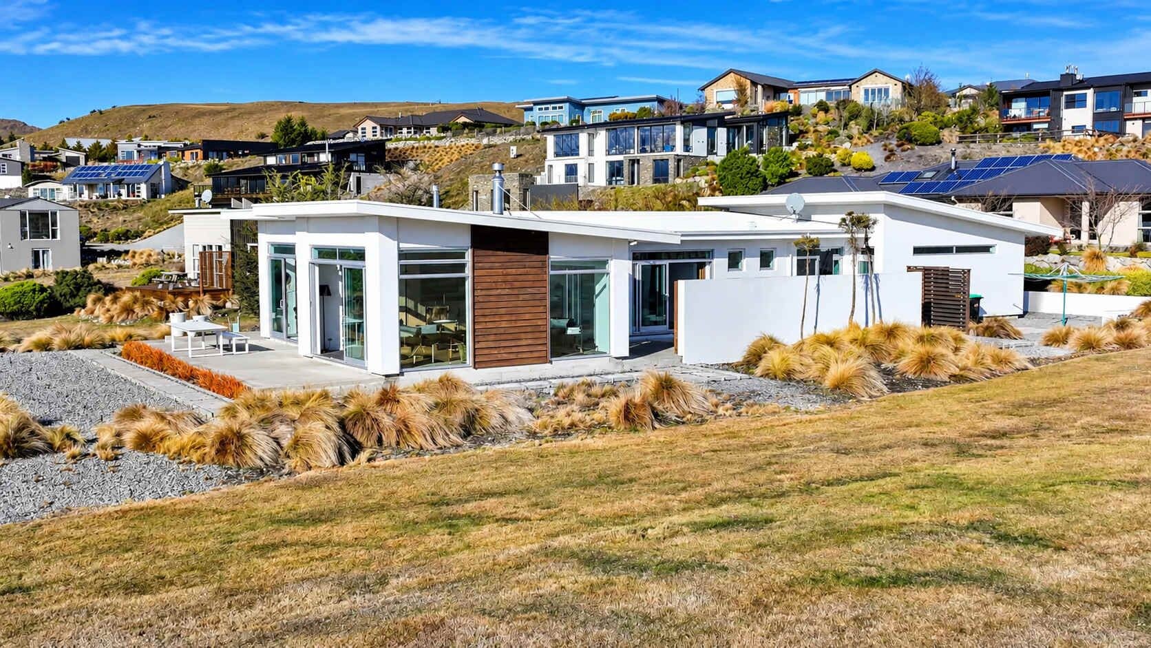 A modern house with a flat roof, large windows, and solar panels.