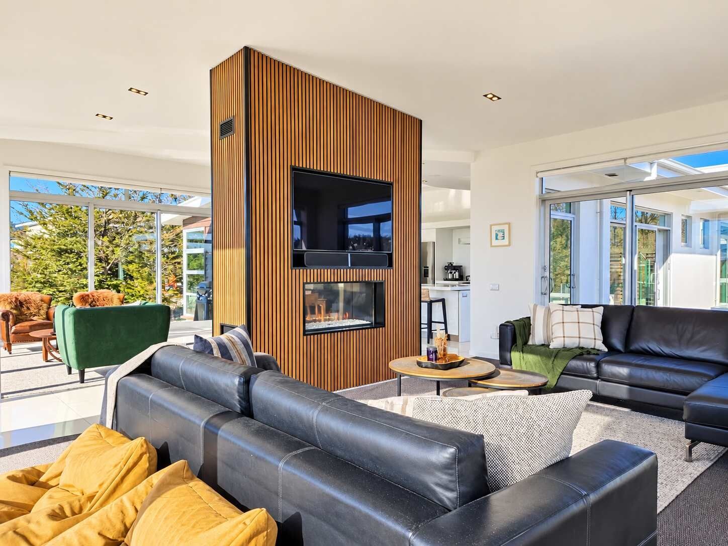 A modern living room with a fireplace, leather sofas, and a view of the outdoors.