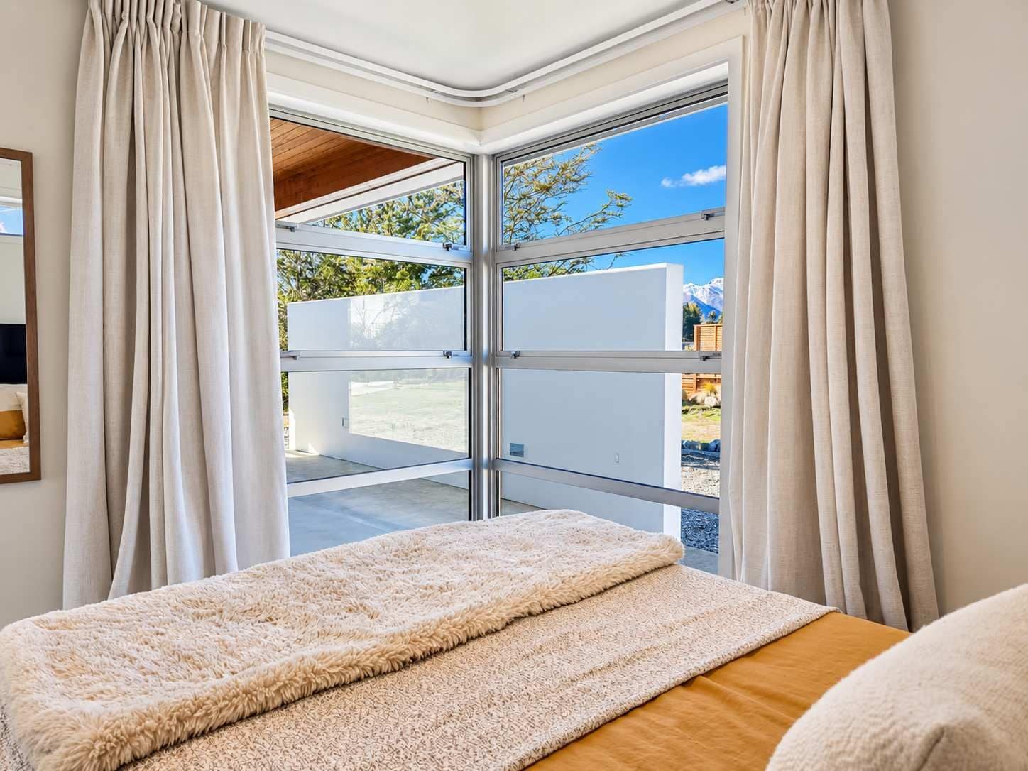 A bedroom with a large window, a fluffy rug, and a bed.
