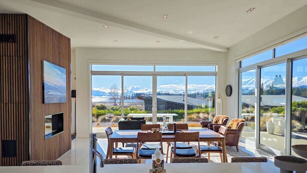 A modern kitchen with a large island, a dining area with a view of mountains, and a cozy seating area with a fireplace.