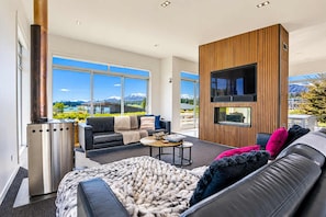 A modern living room with a fireplace, a sofa, a coffee table, and a TV mounted on a wooden wall.