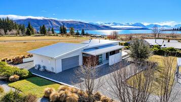 A modern house with a garage, surrounded by a well-maintained lawn and a view of mountains and a lake.