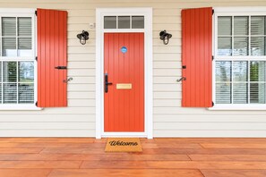 A house with a red door, white shutters, and a welcome mat.