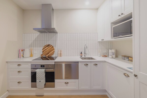 Une cuisine moderne avec des meubles blancs, des appareils en acier inoxydable et un four à micro-ondes encastré.