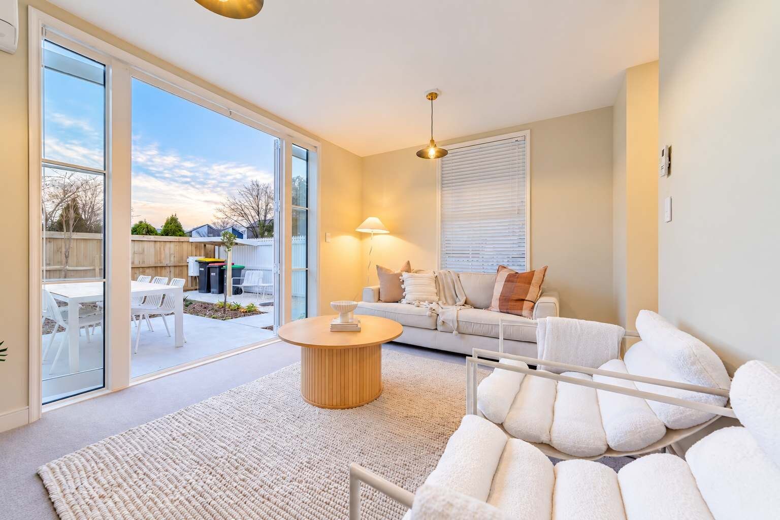 Un salon moderne avec un canapé, une table basse et une vue sur le jardin arrière.