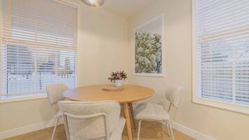 A dining area with a round table, four chairs, and a vase with flowers.