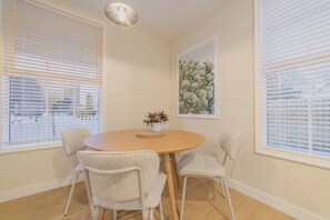 A dining area with a round table, four chairs, and a vase with flowers.