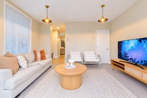 A modern living room with a sofa, chairs, a coffee table, and a TV.
