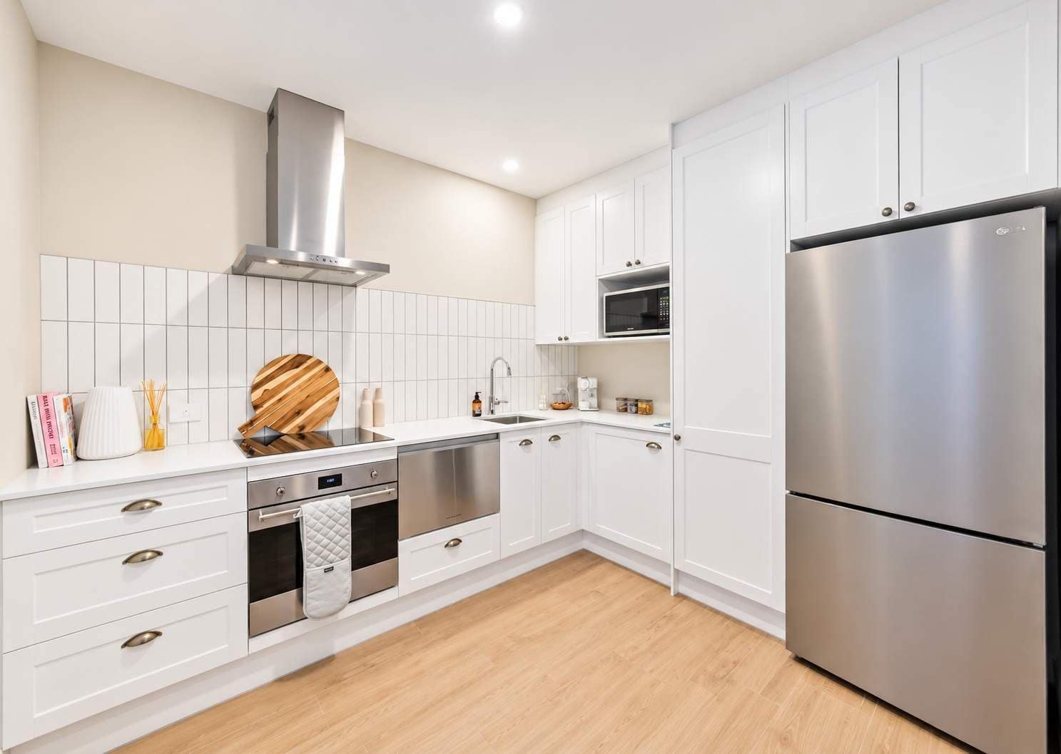 Una cocina moderna con muebles blancos, electrodomésticos de acero inoxidable y encimera de madera.
