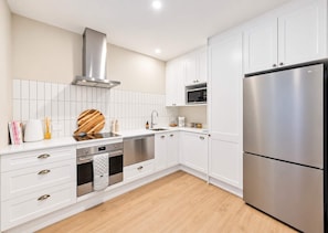 A modern kitchen with white cabinetry, stainless steel appliances, and a wooden countertop.