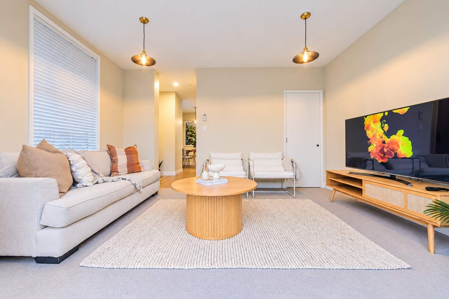 Uma sala de estar moderna com sofá, cadeiras, mesa de centro e televisão.