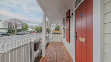 A wooden porch with a red door, white railings, and a mailbox.