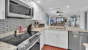 A modern kitchen with white cabinets, a stainless steel microwave, and a black stove. - 2B/2B Fairview Isles 121 Condo, Walk to Beach, Heated Pool! (Fort Myers Beach)