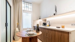 Une cuisine moderne avec un îlot central en bois, une cuisinière encastrée et une fenêtre agrémentée de rideaux.