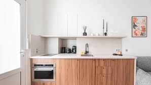 Une cuisine moderne avec des meubles en bois, un four encastré, une machine à café et un évier.