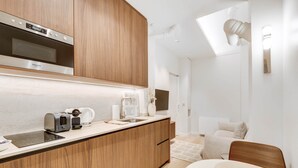 A modern kitchen with wooden cabinets, a built-in oven, and a countertop with a coffee maker and toaster. - Suite Prestige in Pigalle (Paris)