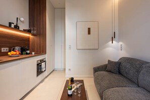 A modern kitchen with a wooden countertop, a built-in oven, and a dining area with a grey sofa. - Luxury design studio in Paris (Paris)