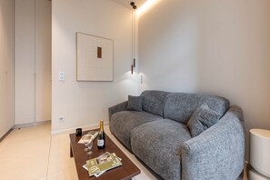A modern living room with a grey sofa, a wooden coffee table with a bottle of champagne, glasses, and magazines. - Luxury design studio in Paris (Paris)