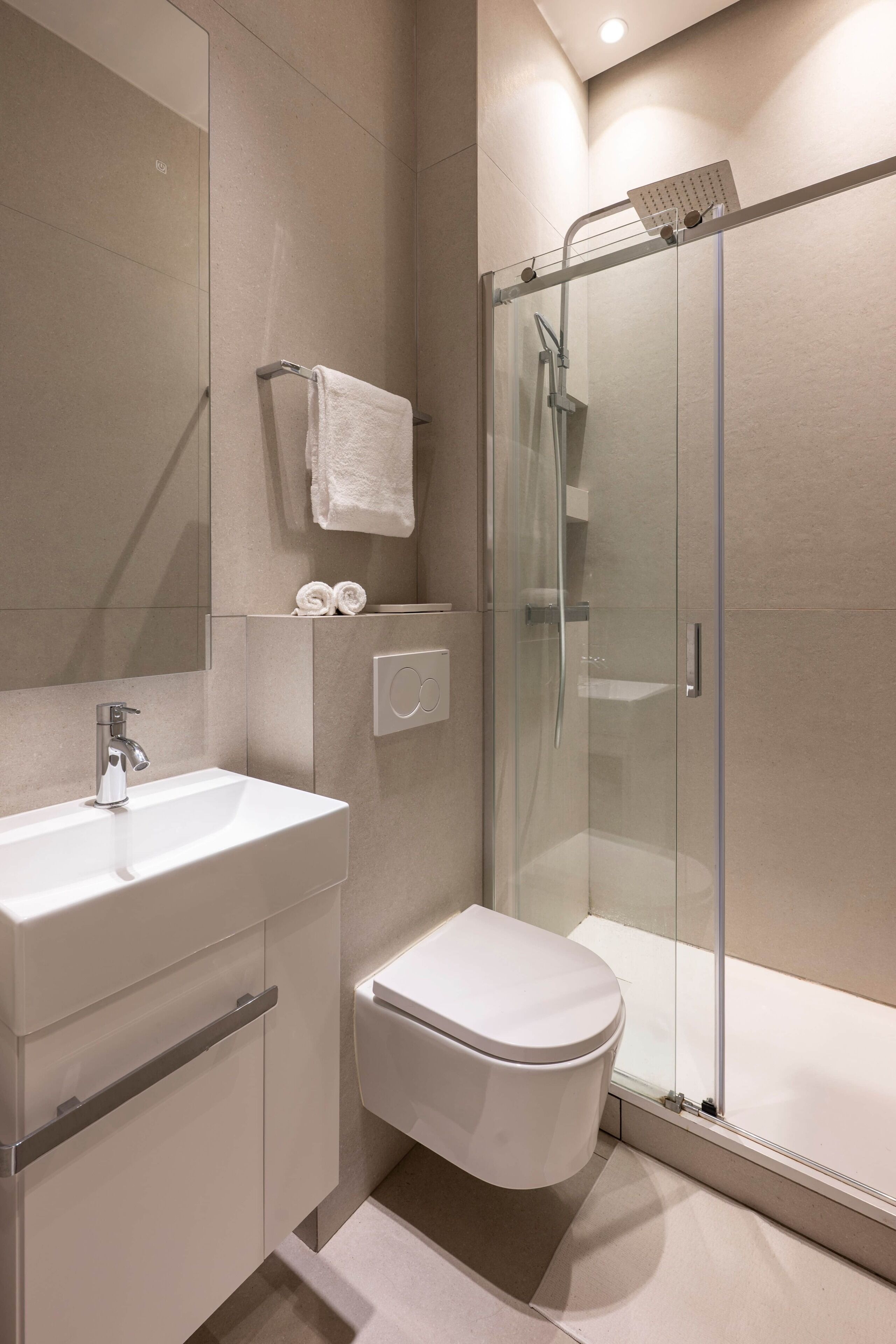A modern bathroom with a glass-enclosed shower, a white sink, and a toilet.