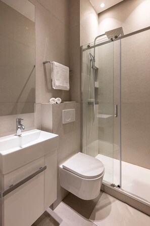A modern bathroom with a glass-enclosed shower, a white sink, and a toilet. - Luxury design studio in Paris (Paris)