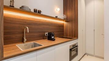 Een koelkast, een oven, een broodrooster, kookgerei, borden en bestek