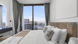 Ein Hotelzimmer mit einem großen Bett, Blick auf die Stadt durch raumhohe Fenster und einem modernen Design.