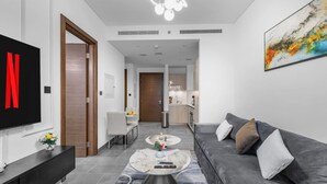 Ein modernes Wohnzimmer mit einer grauen Couch, einem Couchtisch und einem Fernseher an der Wand.