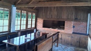 Una cocina rústica con un horno de ladrillo, vigas de madera y una larga mesa de comedor.