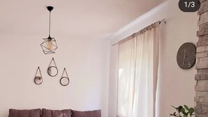 Una sala moderna con un sofá seccional, una mesa de comedor y una isla de cocina. Hay adornos en la pared y un reloj.