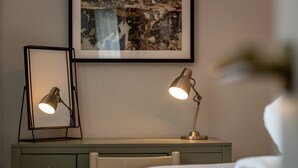 A neatly arranged bedroom with a bed, a desk with two lamps, and a framed picture on the wall. - Skye Sands | St Mary’s Gardens (No 2) (St Andrews)