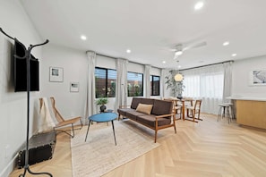Stylish open-concept living area with plenty of natural light. Kick back on the sofa to watch TV or enjoy a meal at the dining table. - La Jolla Luxury 2BR | Tesla Charger + Parking (San Diego)