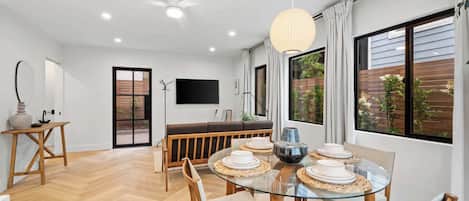 Spacious, light-filled living area with an inviting dining table. Relax on the comfortable couch and enjoy a movie night on the large flat-screen TV.
